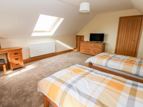 a attic bedroom with two beds and a television at Pant y Gaseg Farm in Ammanford