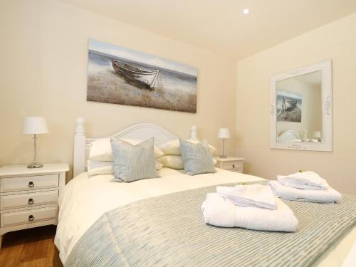 a white bedroom with two beds and a painting on the wall at Elm Cottage in Truro