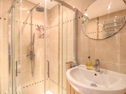 ein Bad mit einem Waschbecken und einer Dusche mit einem Spiegel in der Unterkunft Church Road Annexe in Cinderford