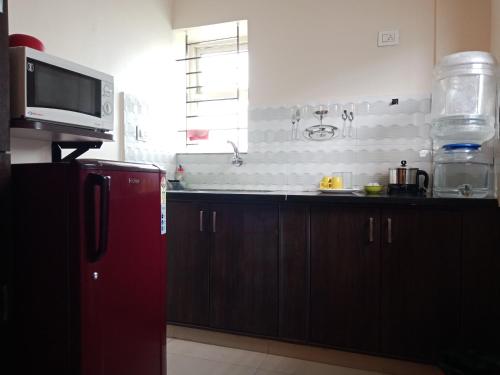 La cuisine est équipée d'un réfrigérateur rouge et d'un four micro-ondes. dans l'établissement Tranquil Serviced Apartments, à Bangalore