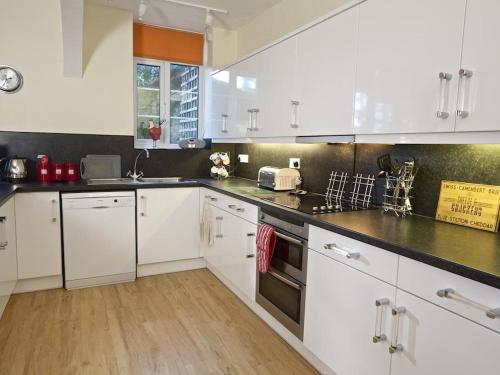 a kitchen with white cabinets and black counter tops at 4 Ringrone in Salcombe