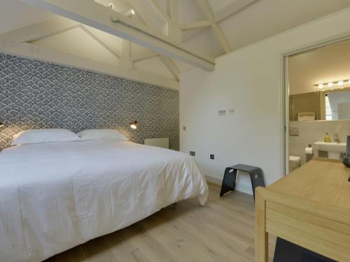 a bedroom with a large white bed and a bathroom at Hayloft in Talaton