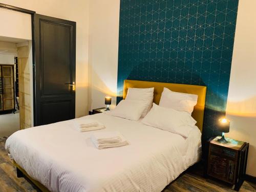 une chambre avec un lit blanc avec un mur bleu dans l'établissement L’Atelier d’Hugla, à Bordeaux
