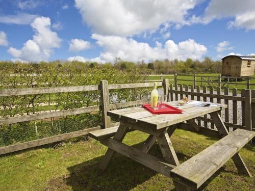 a wooden picnic table with a bottle of wine on it at Cloverwell in Kingsbridge