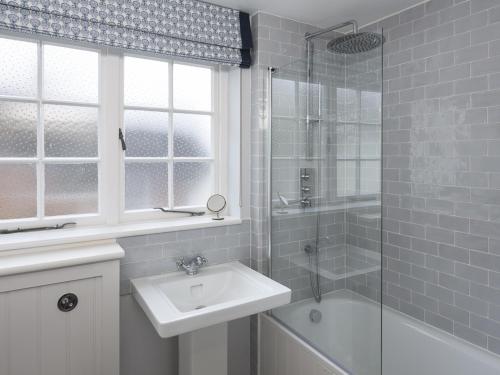 a white bathroom with a sink and a shower at 11 Robinsons Row in Salcombe