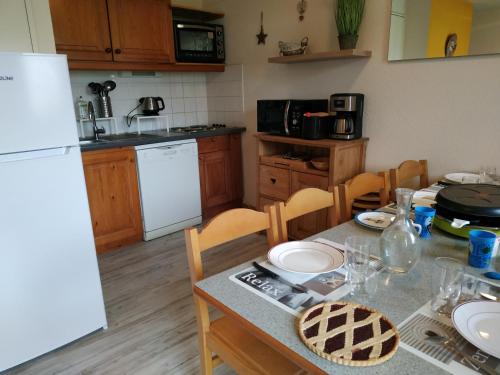 a kitchen with a table and a white refrigerator at Appt 10p Wifi Confort 150m activités, pistes, commerces in Superdevoluy