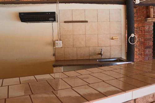 cocina con encimera de azulejos y fregadero en Die Huis - Self Catering, en Bela-Bela