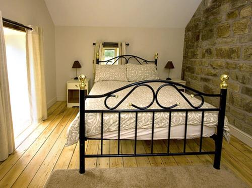 a bedroom with a black bed with a stone wall at Goldcrest in Meerbrook