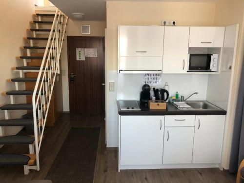 eine Küche mit weißen Schränken und einer Wendeltreppe in der Unterkunft Apartment 47 in Sindelfingen