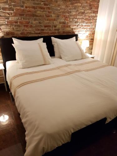 a large white bed in a room with a brick wall at All Exclusive Apartments in Dordrecht