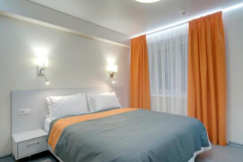 1 dormitorio con 1 cama y una ventana con cortinas de color naranja en Arena Summit Apart Hotel en Kiev