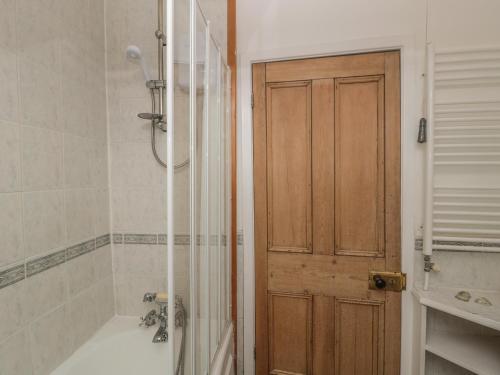 a bathroom with a shower and a wooden door at 31 Peth Head in Wooler