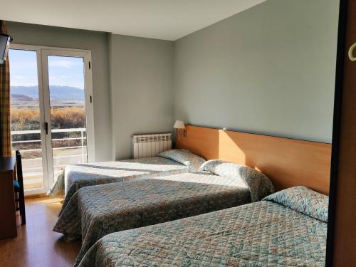two beds in a room with a window at Hotel Área de Calahorra in Calahorra