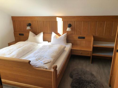 a bedroom with a large wooden bed with white pillows at Gästehaus Aurikel 16 in Fischen