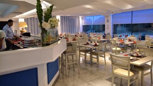 un restaurante con mesas y sillas blancas y una barra en Gran Hotel Fontainebleau en San Clemente del Tuyú