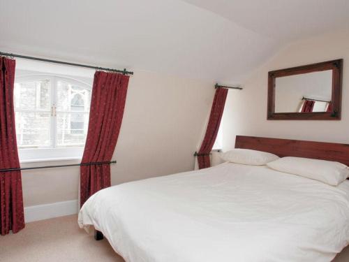 1 dormitorio con 1 cama con cortinas rojas y espejo en Aeolus House, en Dartmouth