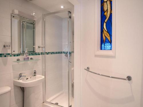 a white bathroom with a shower and a sink at Aeolus House in Dartmouth