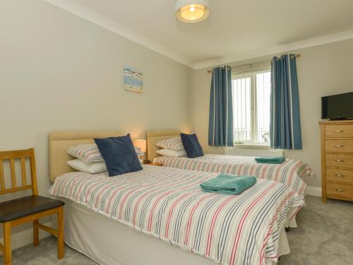 um quarto com 2 camas, uma televisão e uma cadeira em 3 Tarifa em Bigbury on Sea