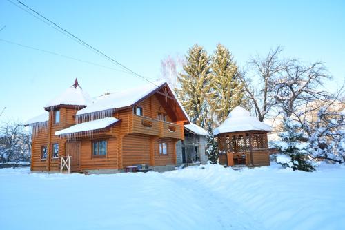 a wooden cabin with snow on the roof at Котедж Соняшник in Verkhovyna