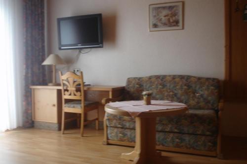 a living room with a couch and a table and a tv at Pension Sigle in Dingolfing