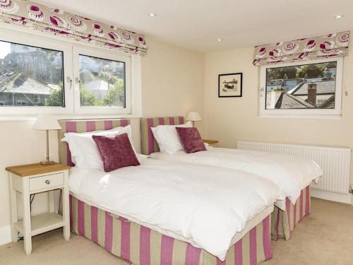 Un dormitorio con dos camas y dos ventanas. en Quayside, en Salcombe