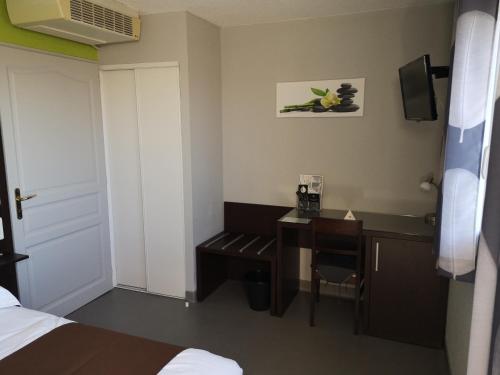 een hotelkamer met een bureau en een bed bij Villa Motel in Stenay