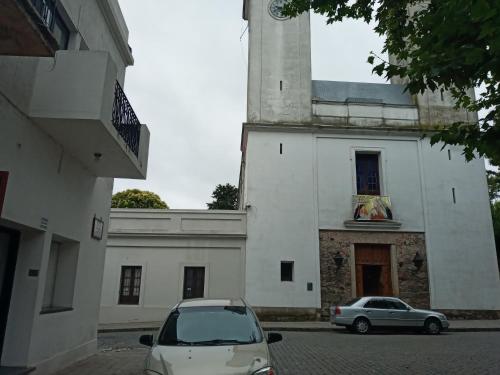 two cars parked in front of a white building at Hermosa casa en el corazón del barrio histórico in Colonia del Sacramento