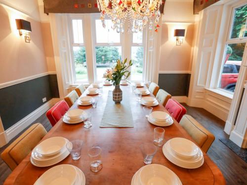 a dining room with a long table with chairs and a chandelier at Roseburn in Pitlochry