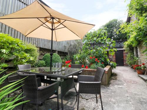 a patio with a table and chairs with an umbrella at The Cider Barn in Kingsbridge