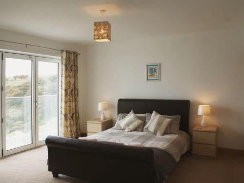 a bedroom with a bed and a large window at Seagulls Perch in Mawgan Porth
