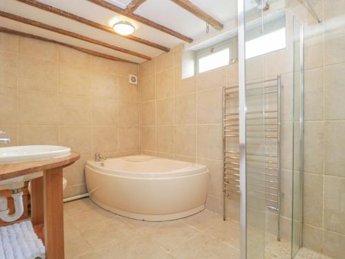 a bathroom with a tub and a glass shower at The Barn in Honiton