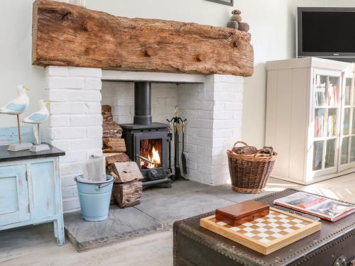a living room with a brick fireplace and a chess board at 3 Elm Cottage in Minehead