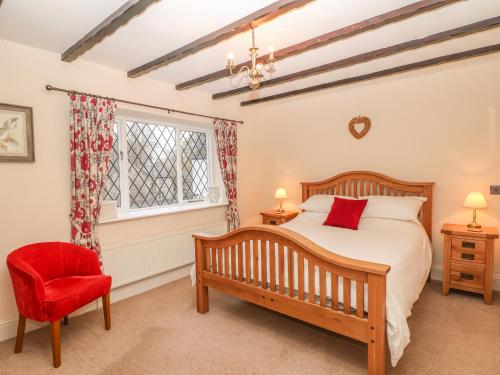 ein Schlafzimmer mit einem Bett und einem roten Stuhl in der Unterkunft Laburnum Cottage in Castleton