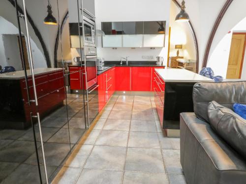 a kitchen with red cabinets and a couch at Penthouse St Mary's Church in Moffat