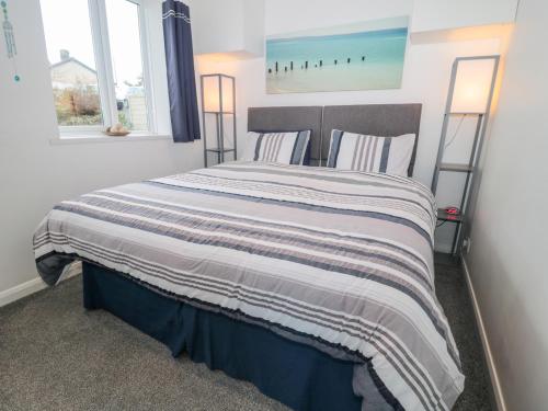 a bedroom with a bed with a striped blanket at Bracken Barn Cottage in Morpeth