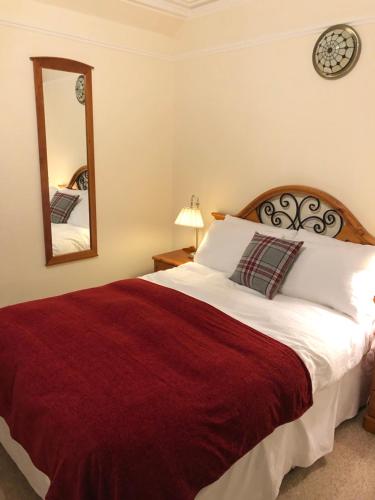 a bedroom with a large bed and a mirror at Ness House in Inverness