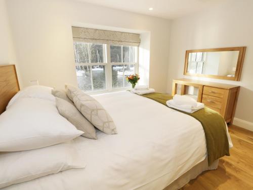 a bedroom with a large white bed and a window at Macan in Ambleside
