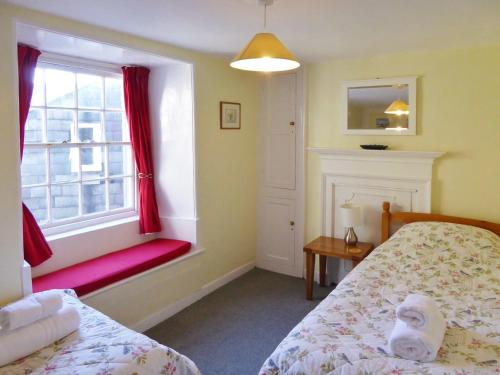 a bedroom with a bed and a window with red curtains at Balcony Cottage in Cawsand