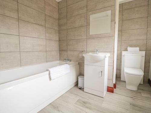 a bathroom with a tub and a sink and a toilet at Berrys Place Farm Cottage in Gloucester