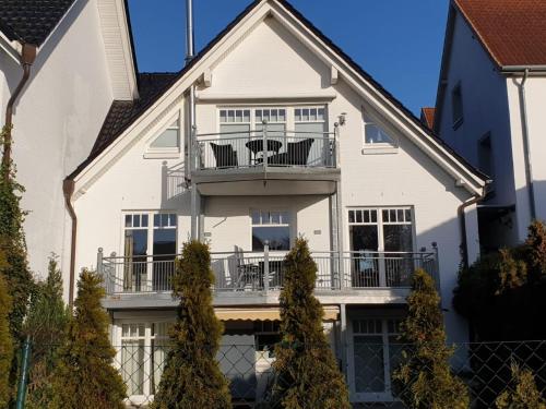 a white house with a balcony and trees at Strandallee 150a in Timmendorfer Strand