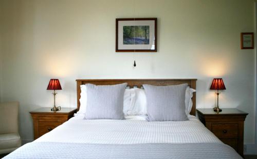 a bedroom with a large white bed with two lamps at Newcourt Barton in Cullompton