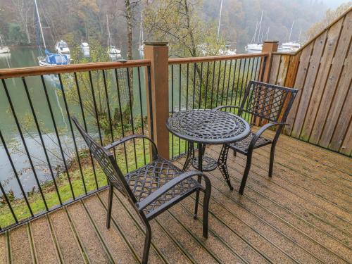 two chairs and a table on a deck with the water at Frost in Ambleside