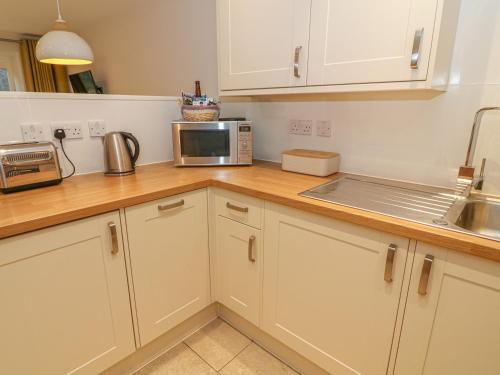a kitchen with white cabinets and a microwave on a counter at Frost in Ambleside
