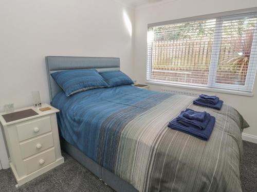 a bedroom with a bed with a night stand and a window at The Nook in Colwyn Bay