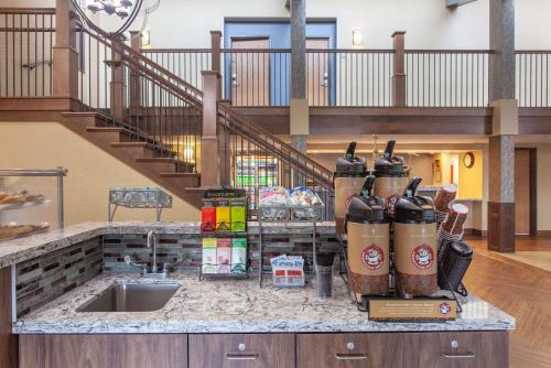 a kitchen counter with a sink and a staircase at AmericInn by Wyndham Mankato Event Center near MSU in Mankato