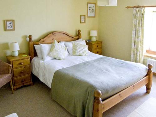 a bedroom with a large bed and two night stands at Bridle Cottage in Settle