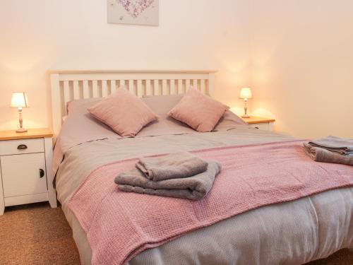 a bedroom with a bed with pink blankets and pillows at Pinner's Cottage in Knighton