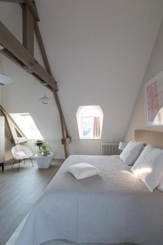 une chambre avec un grand lit et deux fenêtres dans l'établissement La Bourgeoise, à Portbail