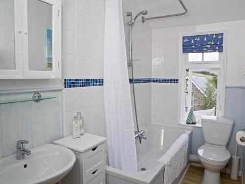 a white bathroom with a tub and a sink and a toilet at St Leonards in Salcombe
