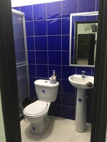 a blue tiled bathroom with a toilet and a sink at Hotel Campestre La María Toro Valle in Toro